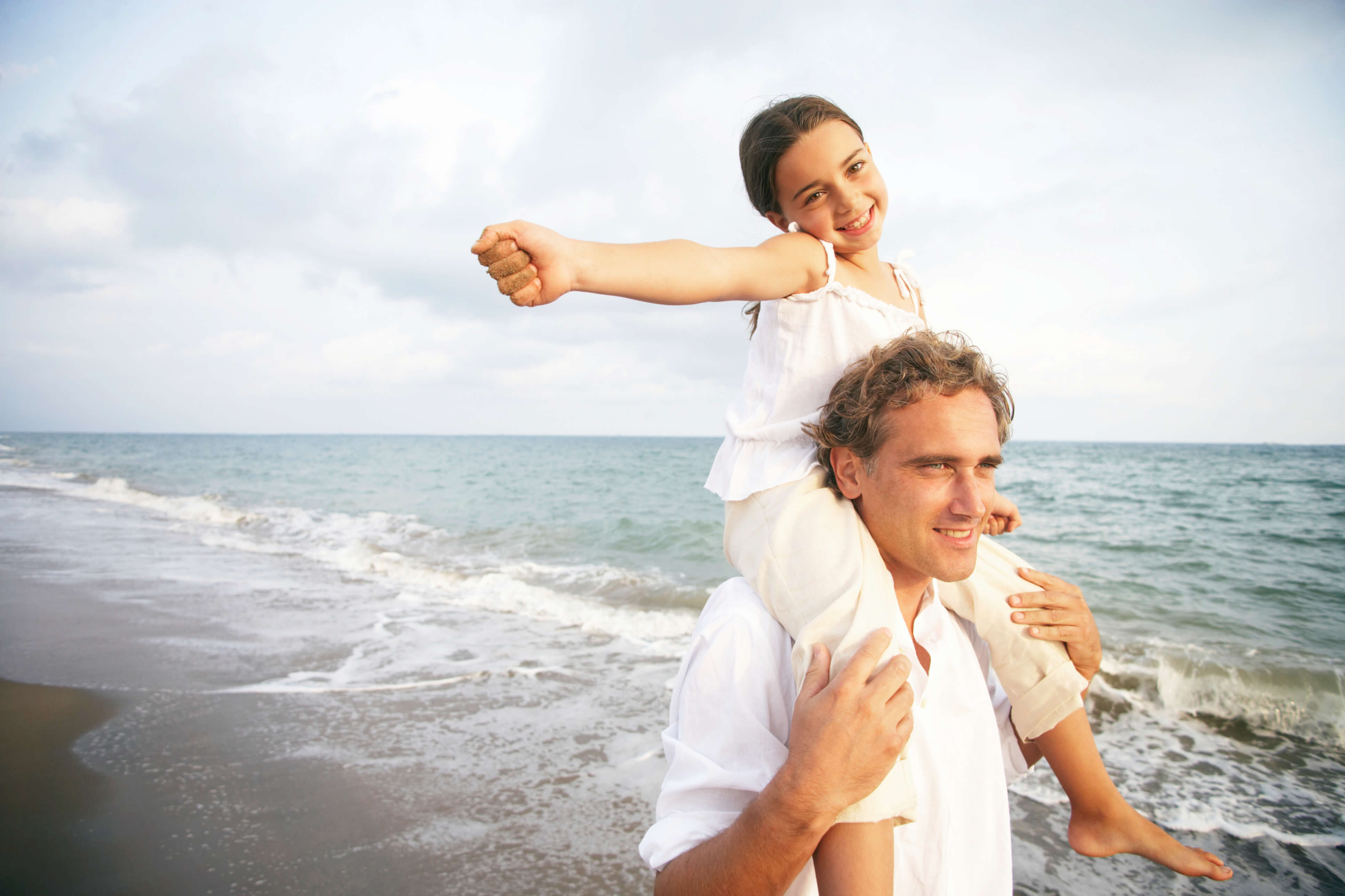 man on beach with young girl on his shoulders