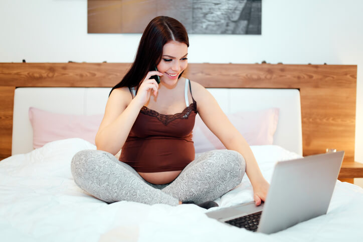 Portrait of positive beautiful pregnant woman in bed